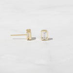 Emerald cut stud earrings in gold from the side angle. 