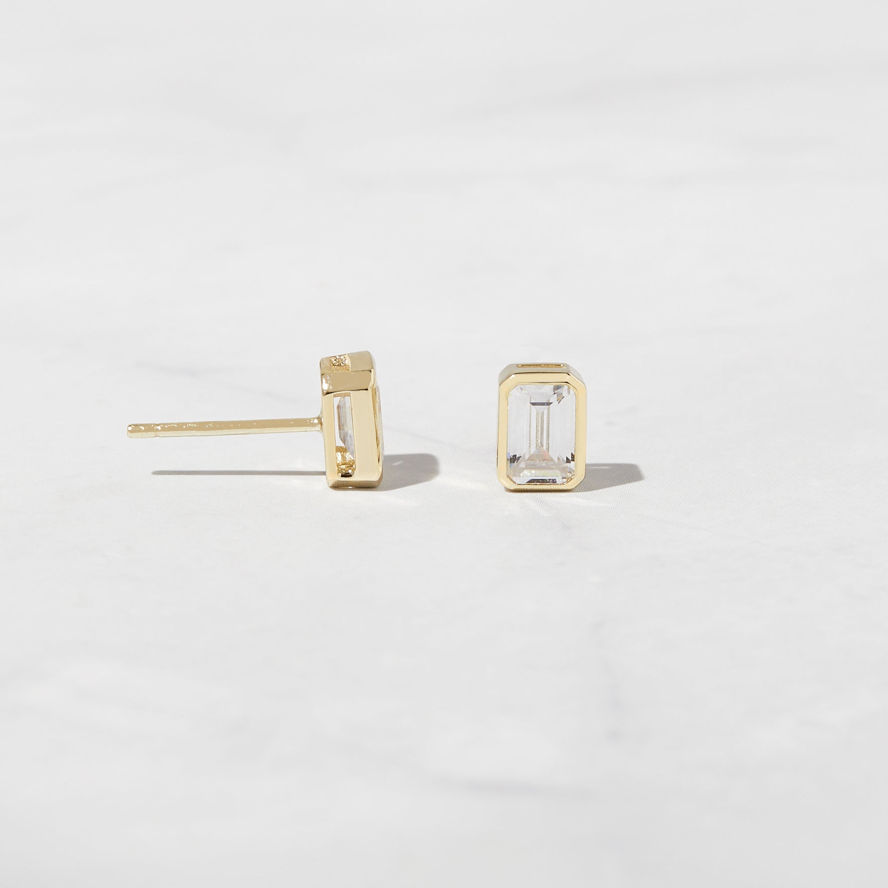 Emerald cut stud earrings in gold from the side angle. 
