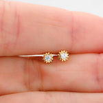 Model holding delicate gold sunburst stud earrings. 