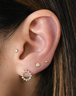 Model wearing sunburst cz studs paired with tiny cz sunburst studs and ball studs. 