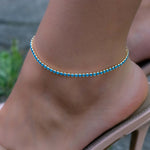 Model wearing heels with classy gold turquoise tennis ankle bracelet