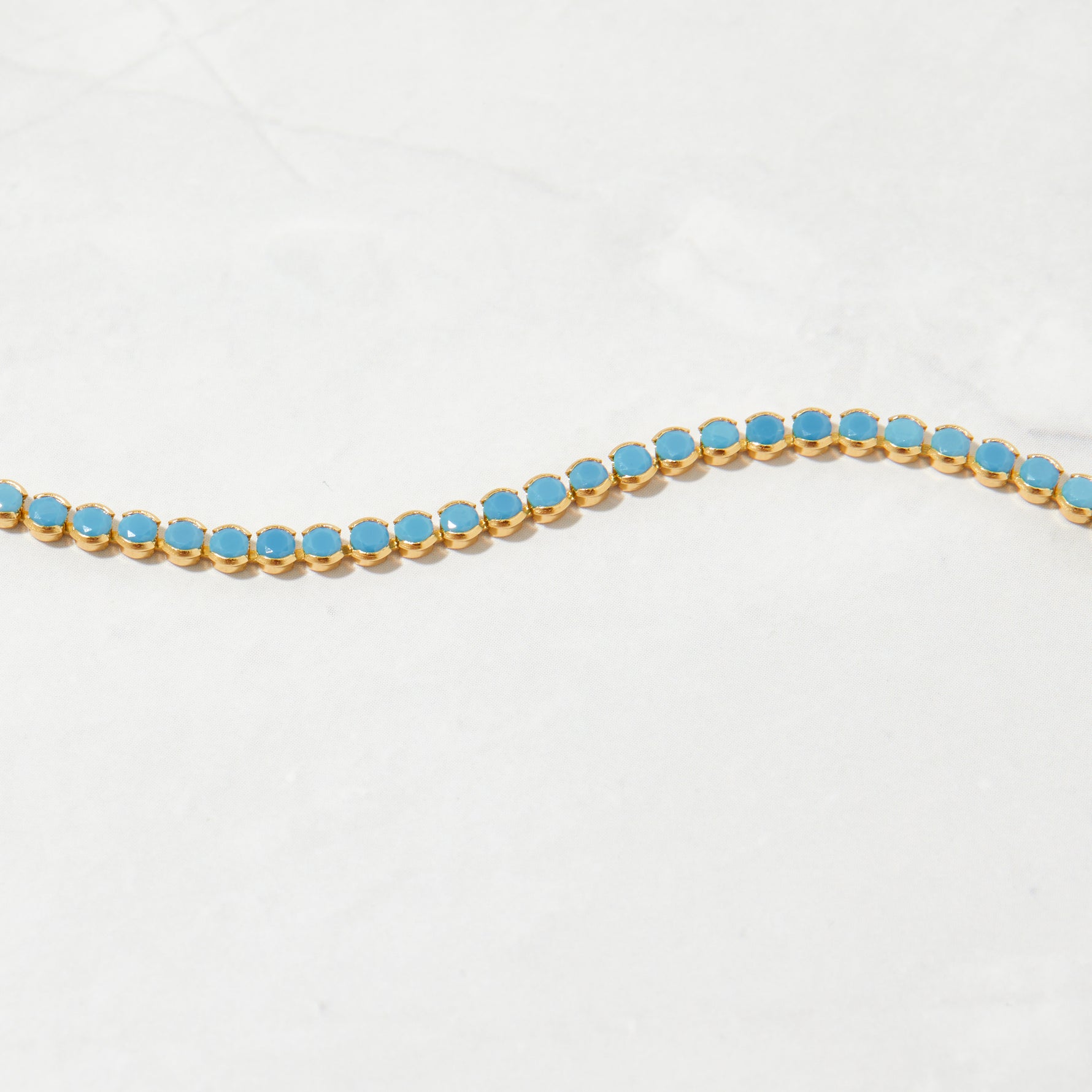 Upclose shot of gold beachy turquoise tennis anklet