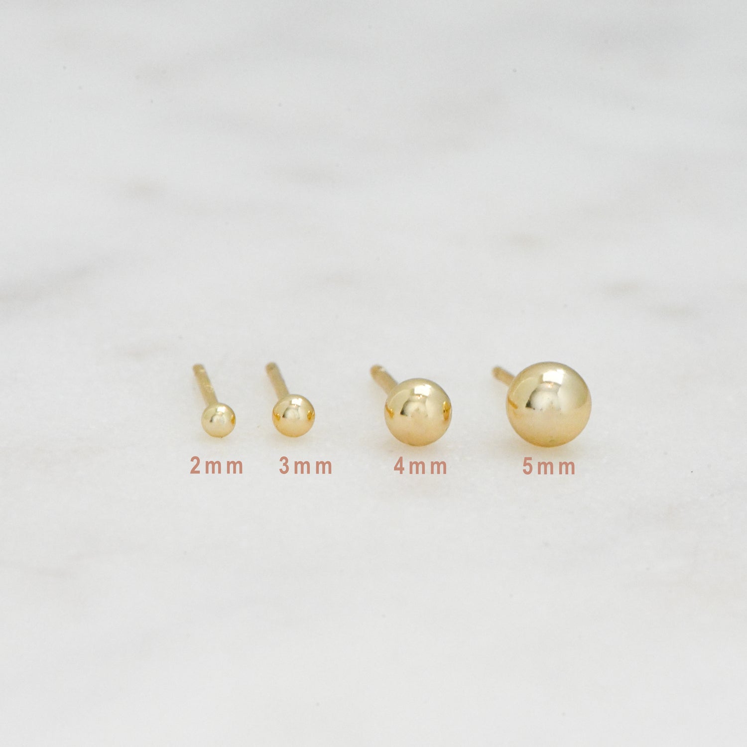 Multiple sizes of gold ball stud earrings.