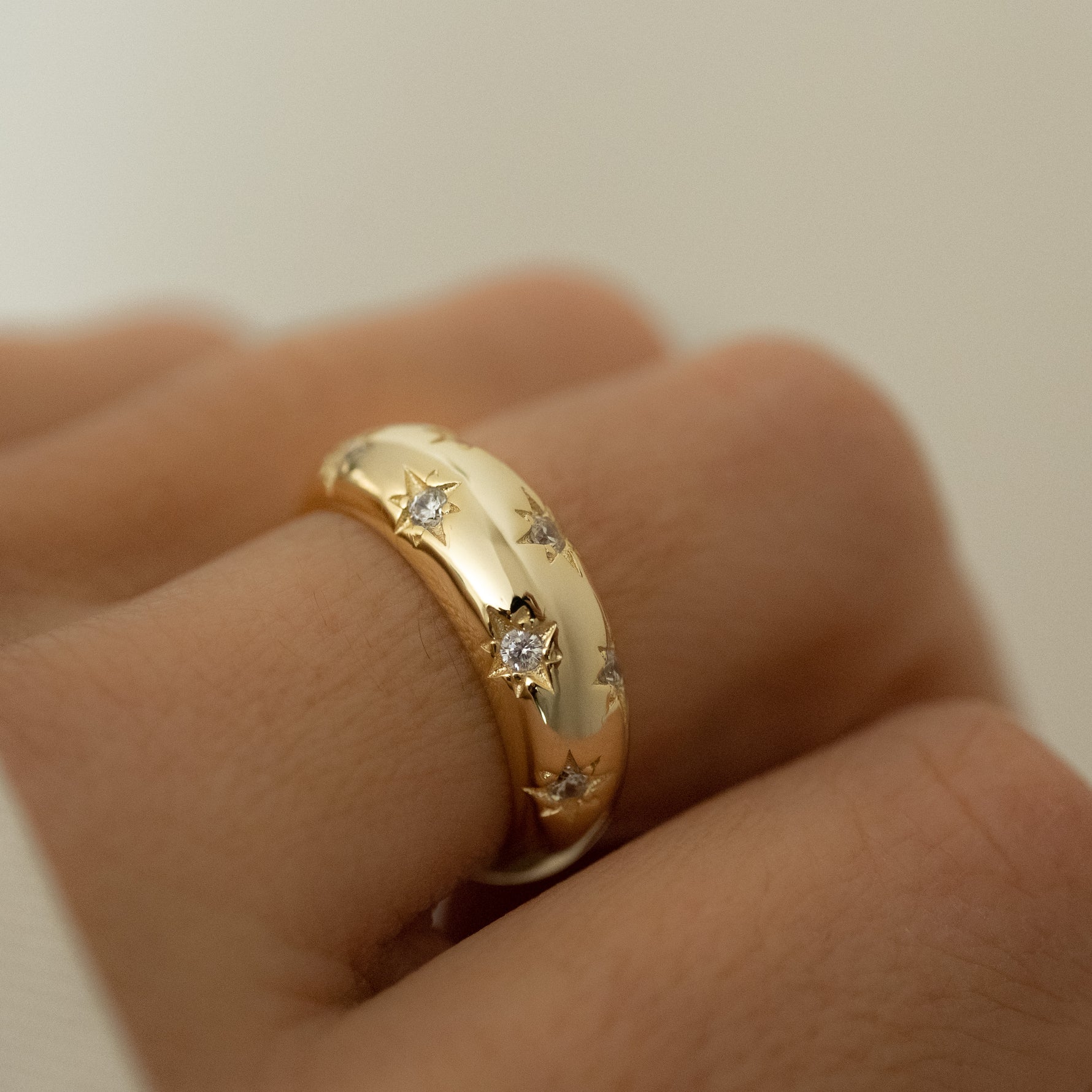 Sterling silver gold plated star studded dome ring with tiny cubic zirconia stars styled on model's hand.