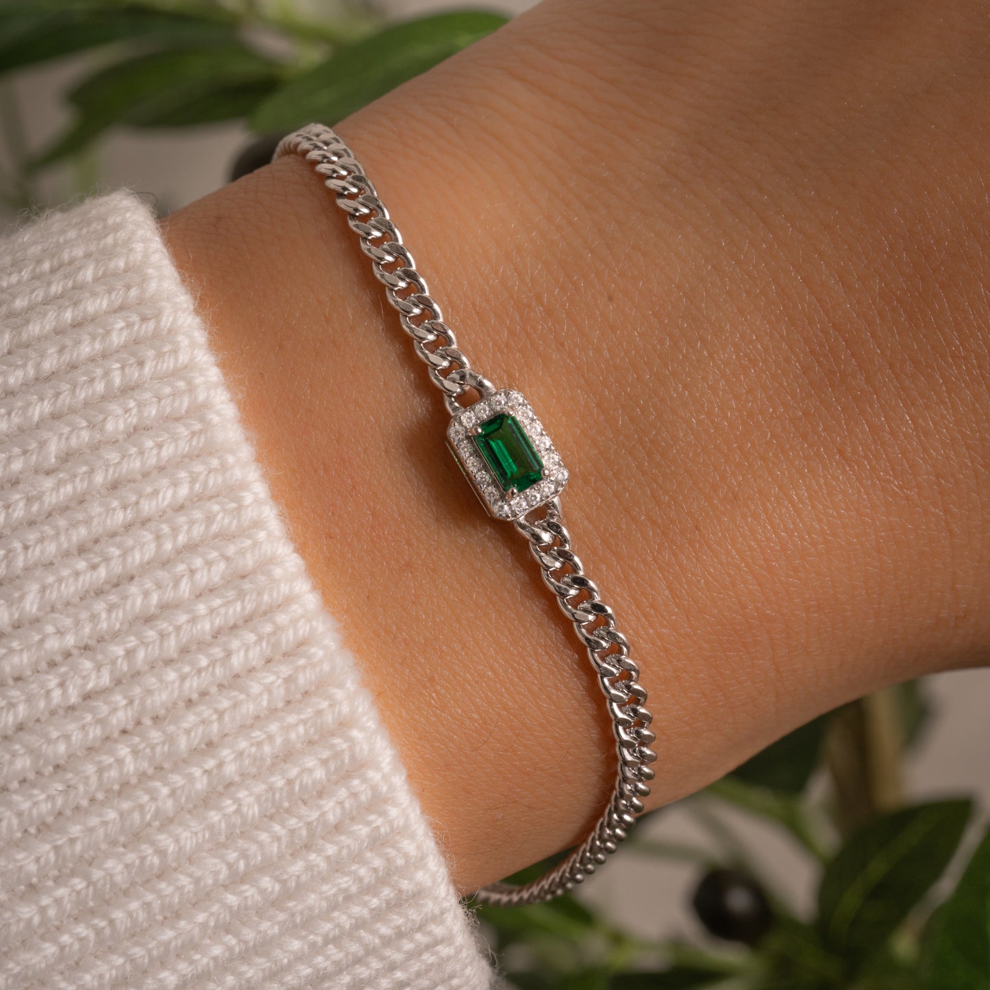 model wearing sterling silver curb chain bracelet with emerald halo charm