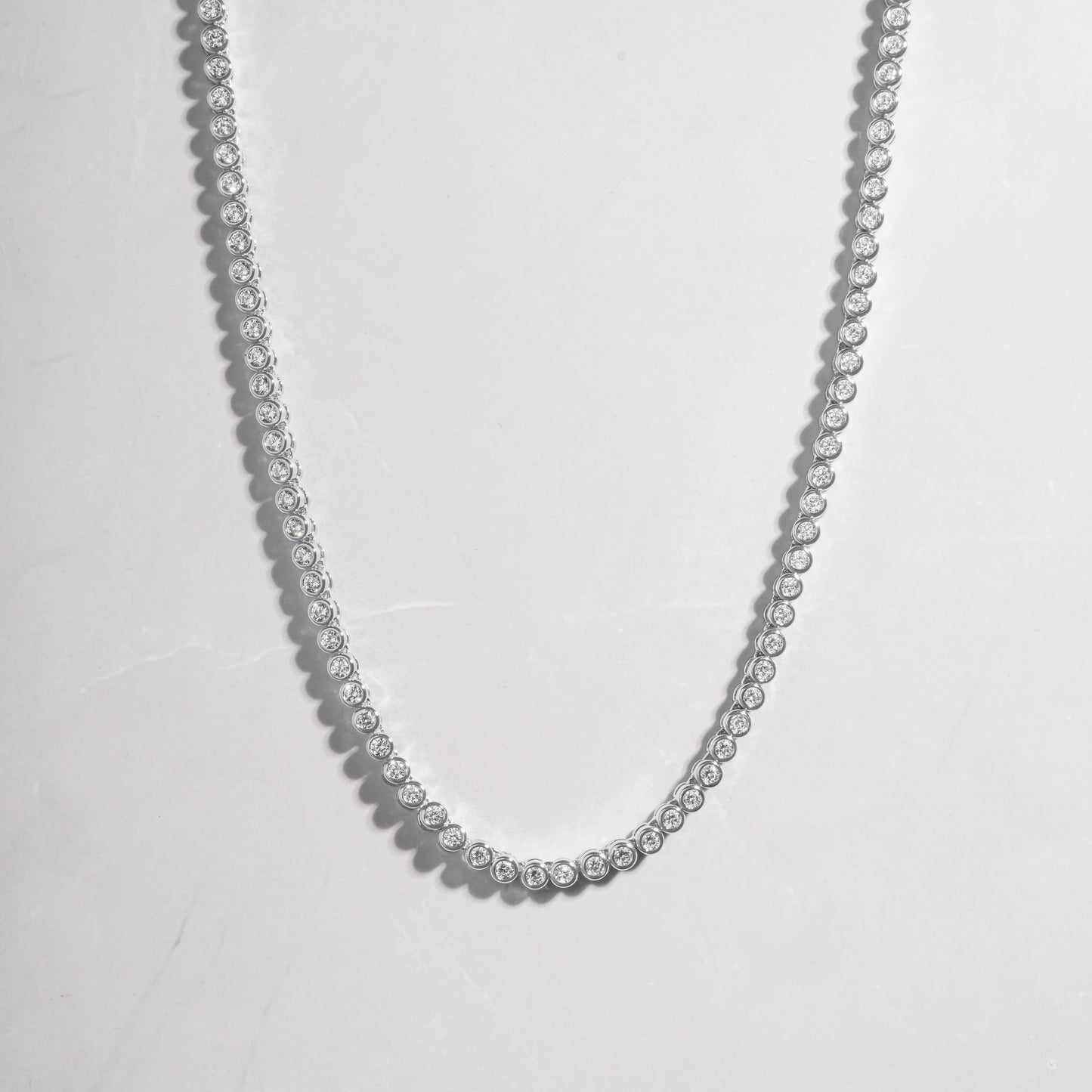 a silver necklace with beads on a white background
