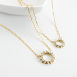 Zoomed-in view of gold plated sunburst necklace with CZ stone on white background