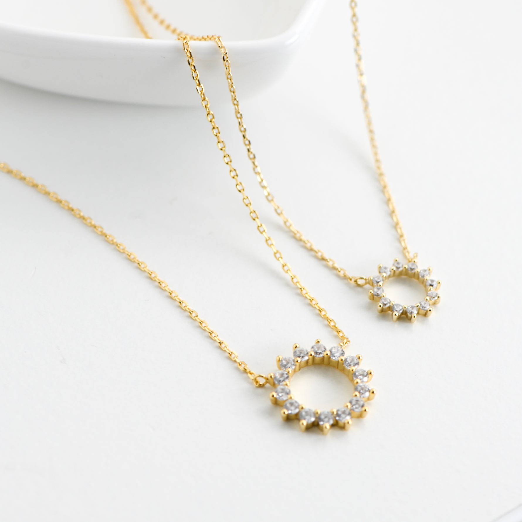 Zoomed-in view of gold plated sunburst necklace with CZ stone on white background