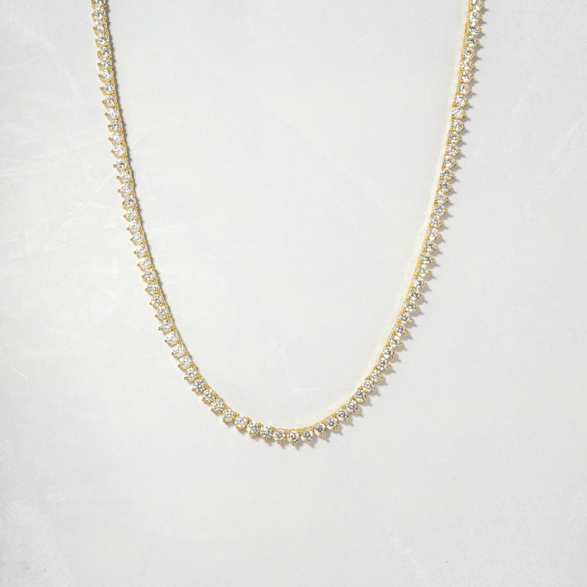 a gold necklace with white stones on a white background