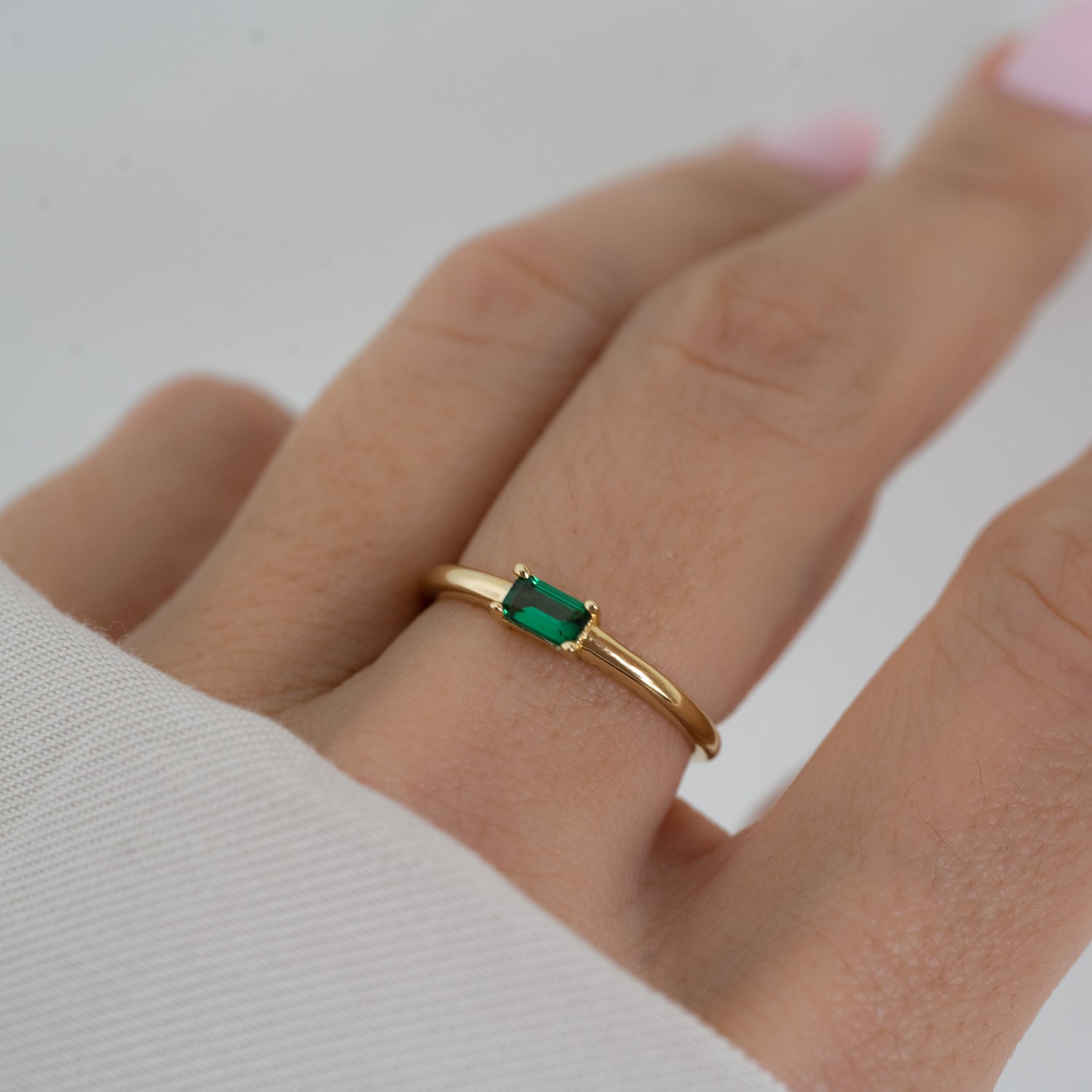 model wearing emerald jewelry featuring emerald baguette ring
