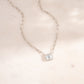a white necklace with a square shaped diamond on a chain