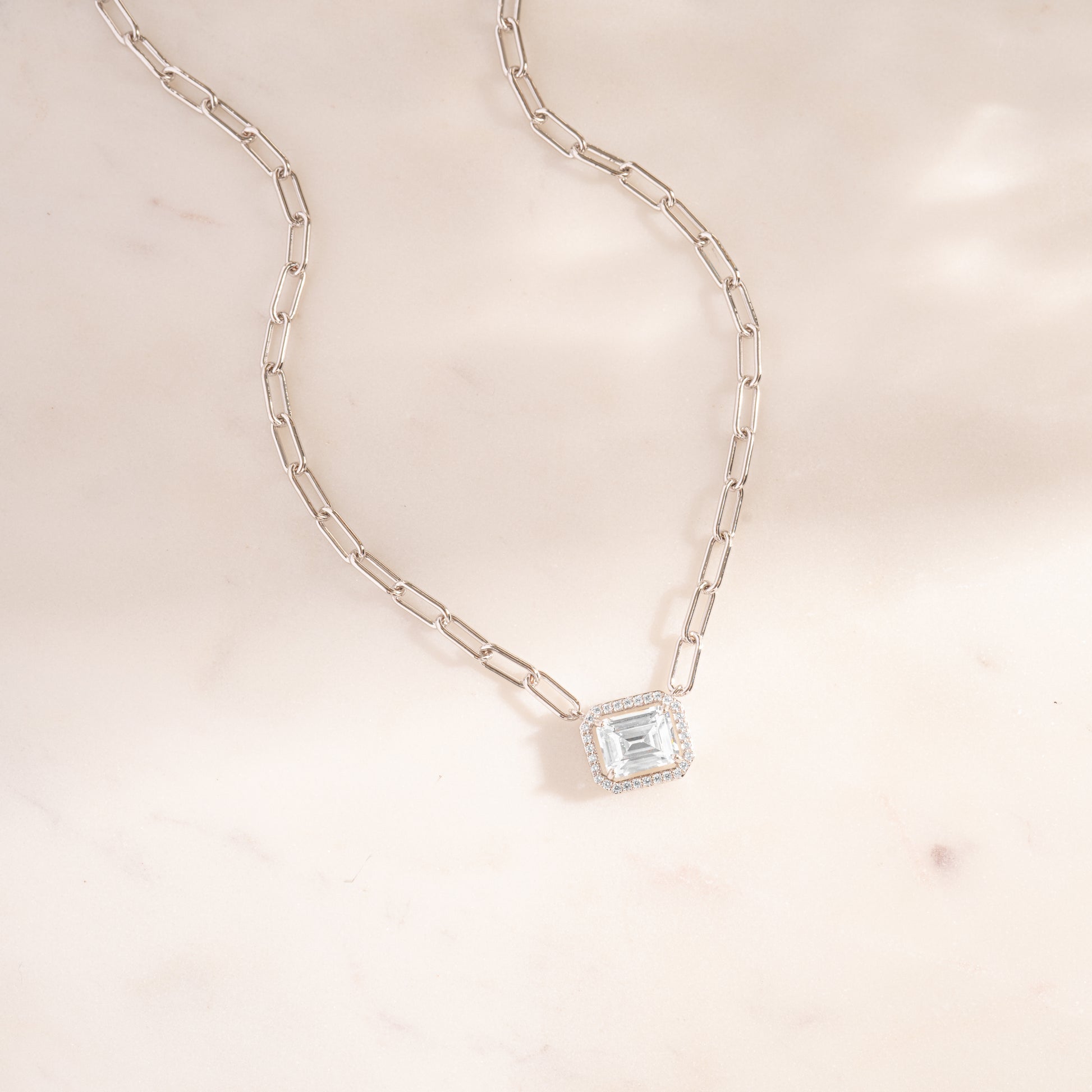 a white necklace with a square shaped diamond on a chain