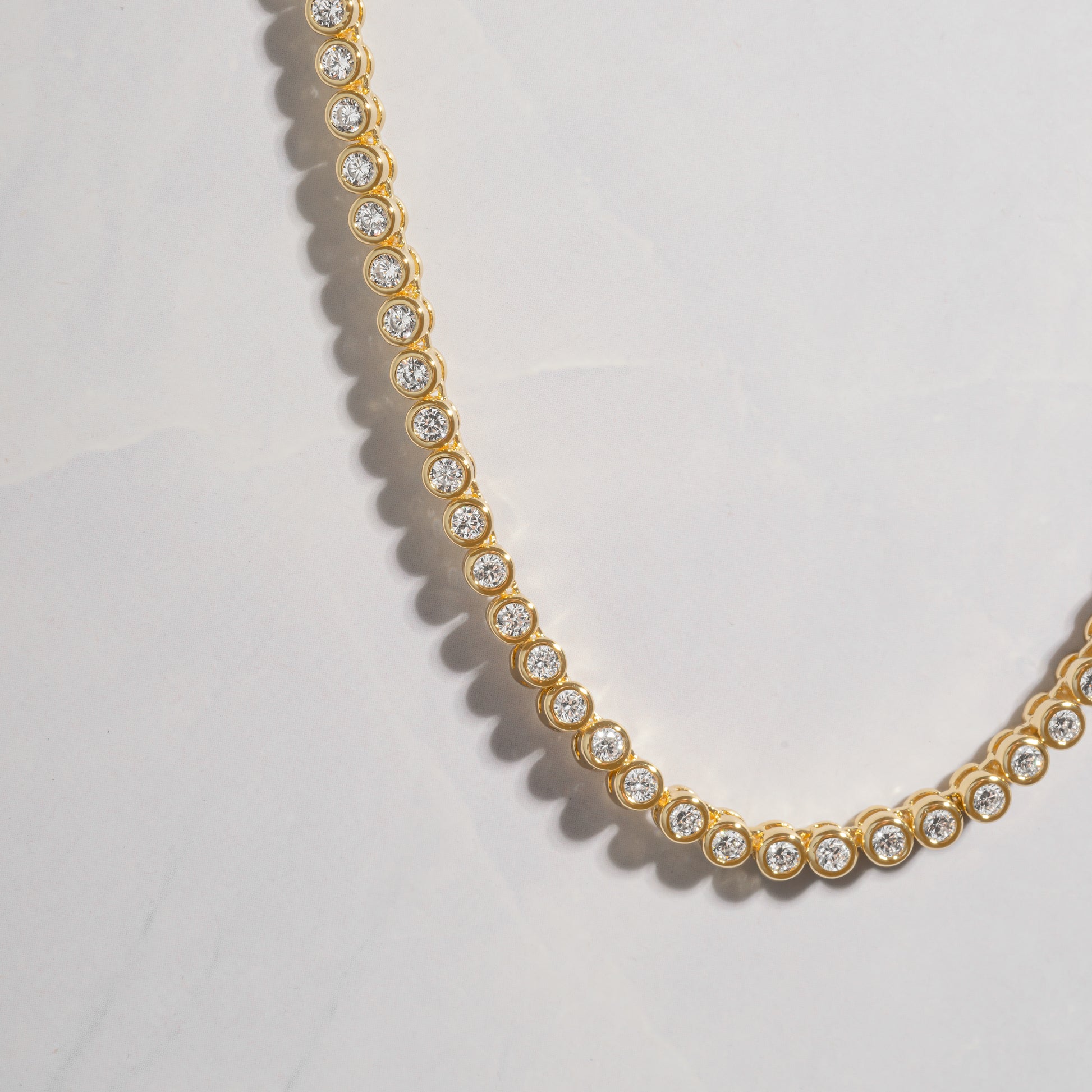 a gold necklace with diamonds on a white background