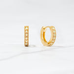 Close up flat-lay tiny hoop earrings. The huggie hoop earrings feature opal stones.