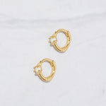 A closeup flat-lay picture of small gold hoop earrings. It features a solitaire opal stone.  