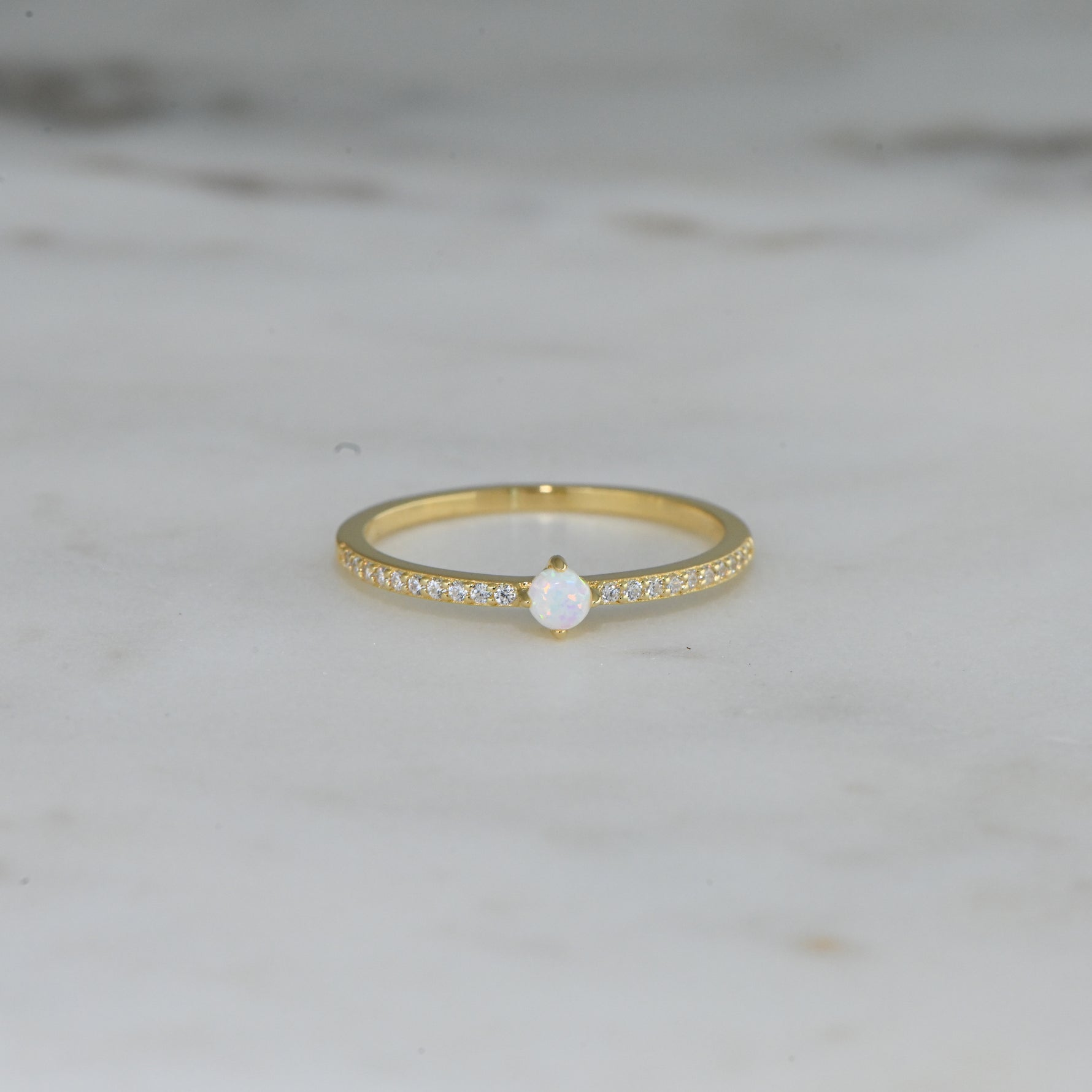 closeup image of dainty opal ring with pave cubic zirconia stones