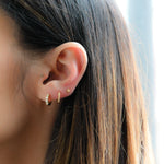 model wearing gold huggie earrings with cz stones, paired with a minimalist pave huggie earring and a 3 ball stud earring 