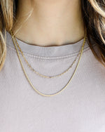 model wearing gold paperclip necklace and dainty twisted chain necklace