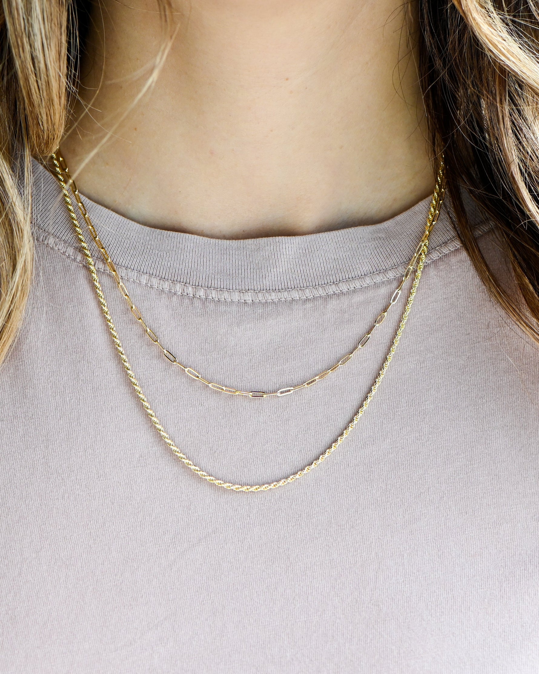 model wearing gold paperclip necklace and dainty twisted chain necklace