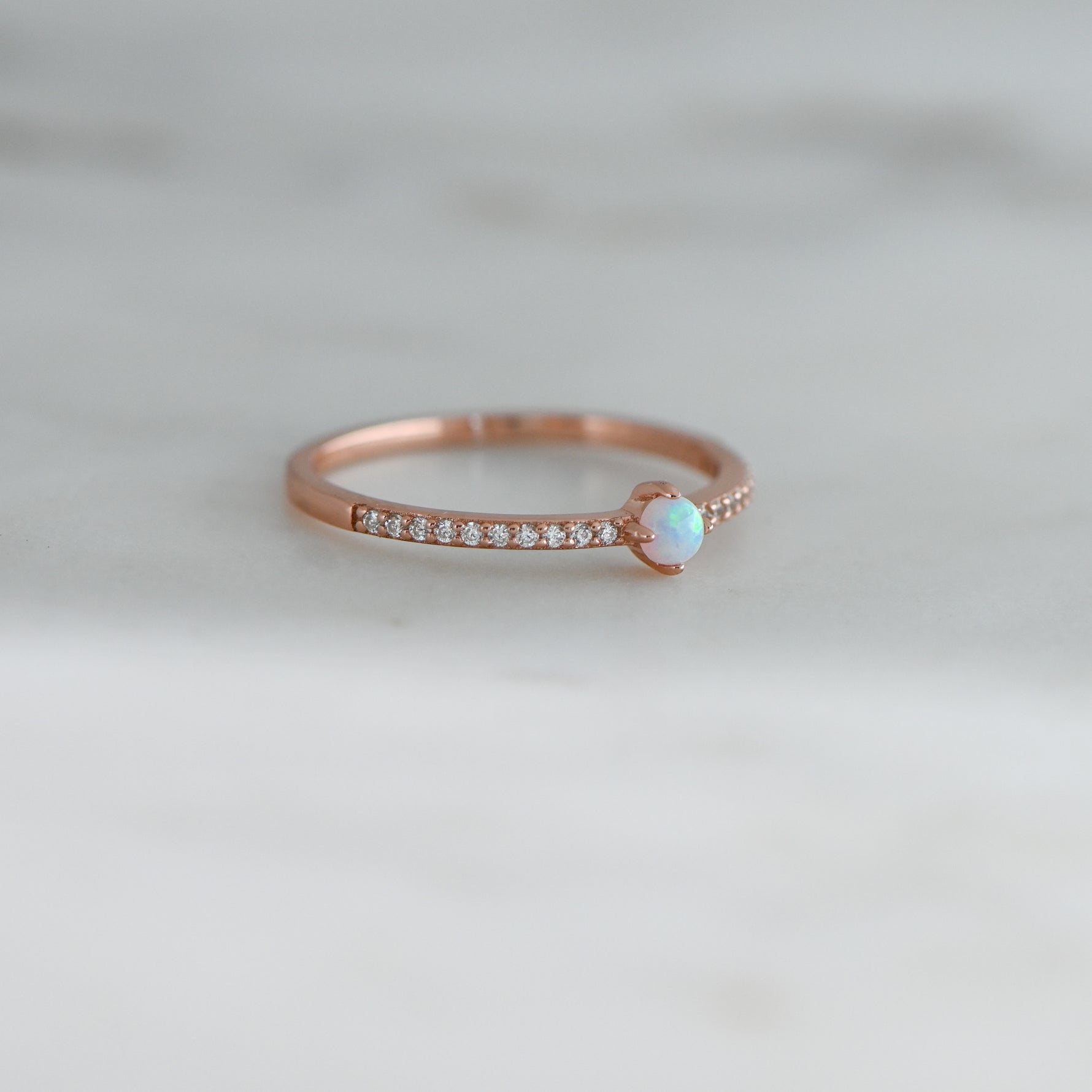 closeup image of rose gold ring featuring opal solitaire stone