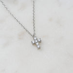 Silver tiny diamond cross necklace with chic, minimalist style showcased on white marble background