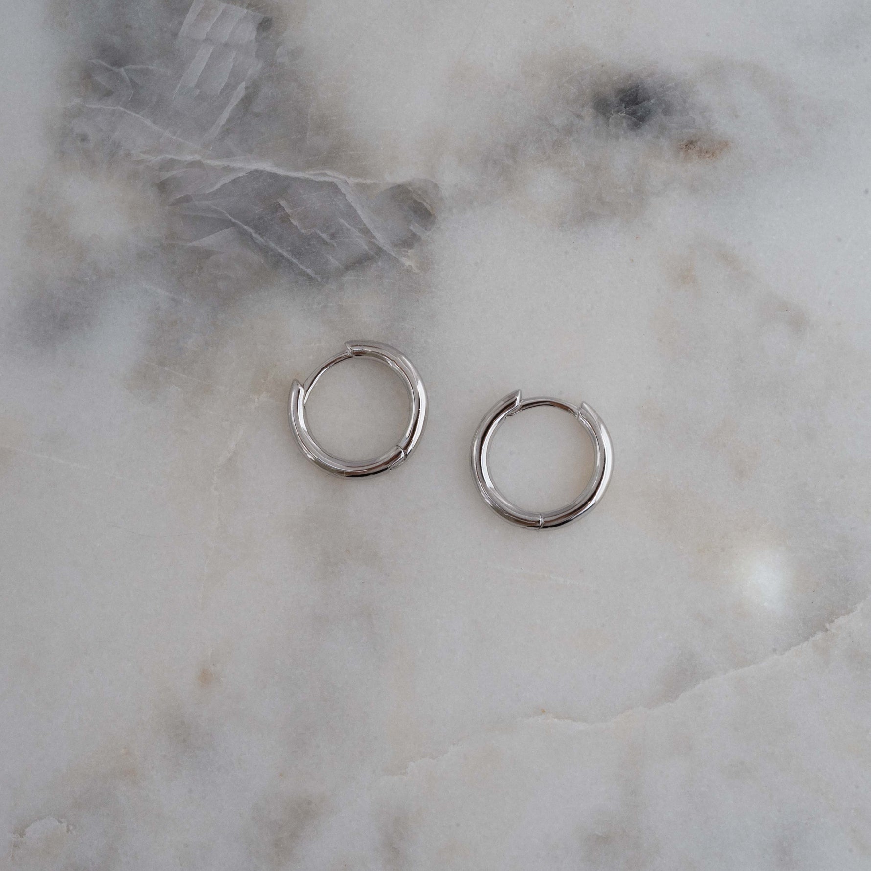 Sterling Silver huggie earrings on marble