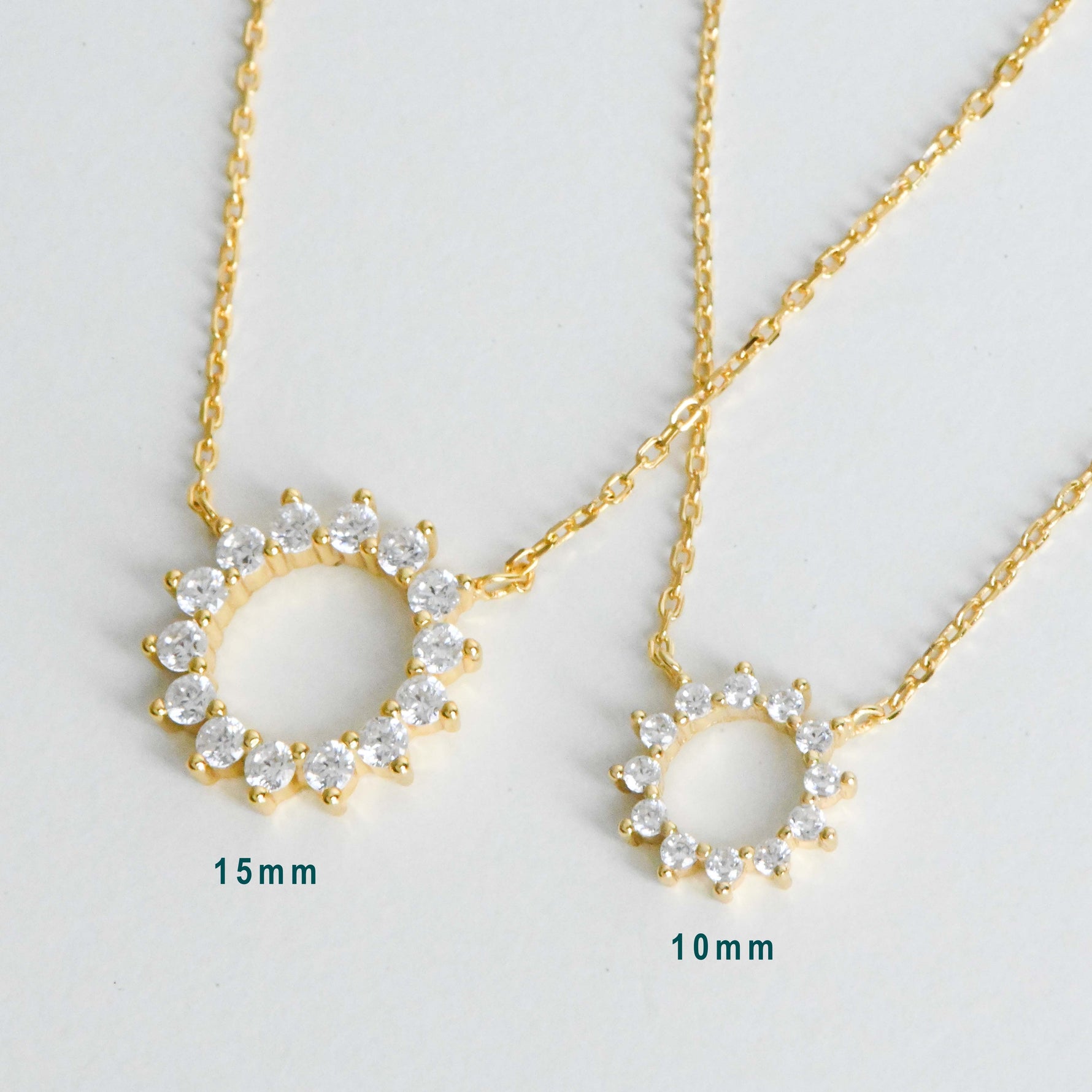 Detailed view of sunburst necklace on delicate chain, showing 10mm and 15mm pendant size