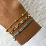 turquoise bracelet, tennis chain bracelet, and beaded ball bracelet on models arm